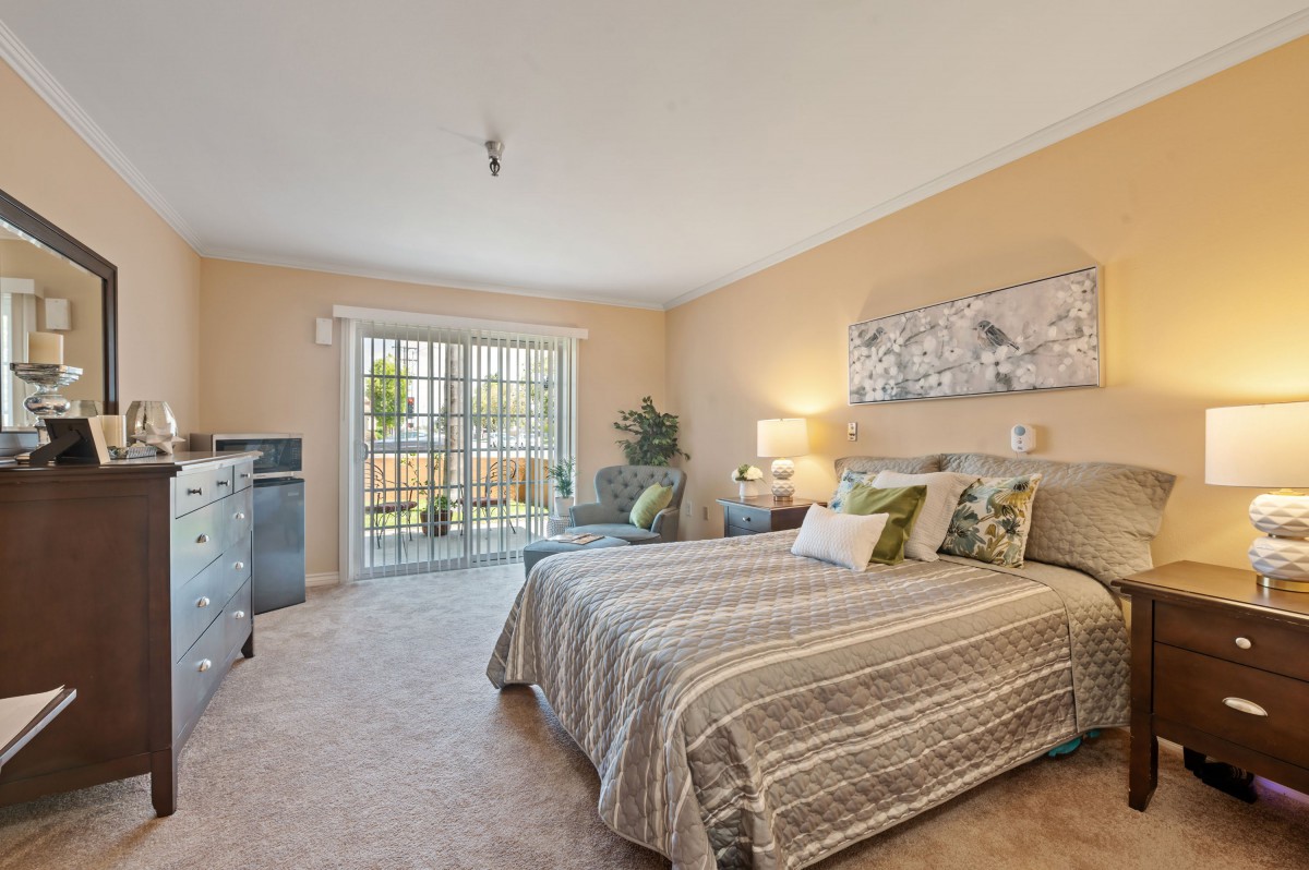 A cozy bedroom with a comfortable bed, soft lighting, and a large window providing natural light.