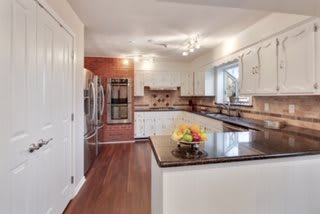 A modern kitchen featuring white cabinets, stainless steel appliances, and a central island with a fruit bowl on top.