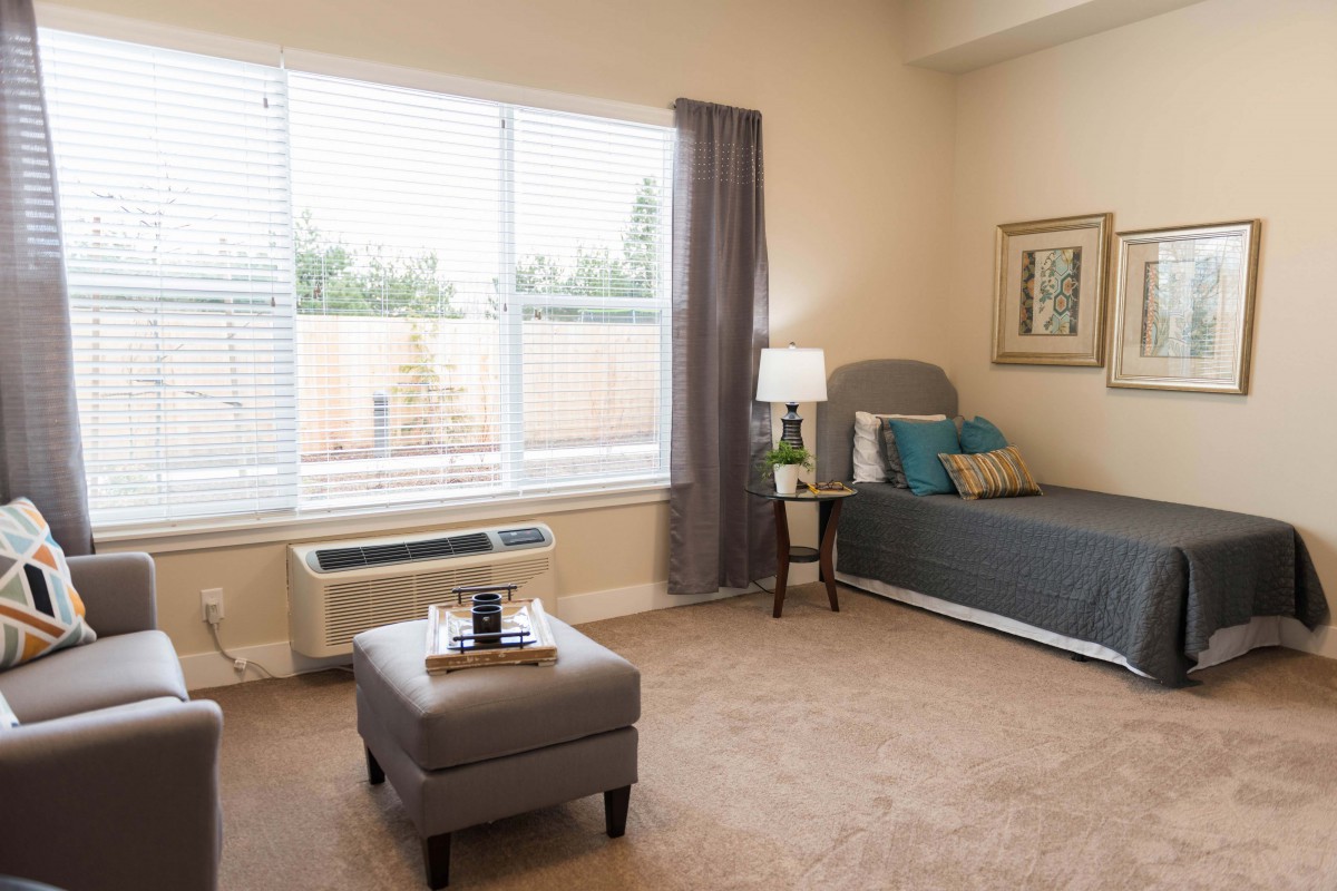A cozy, modern bedroom with a large window, bed, and stylish decor.