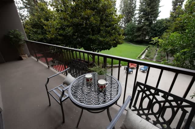 A cozy balcony with a table set for coffee overlooking a lush garden.