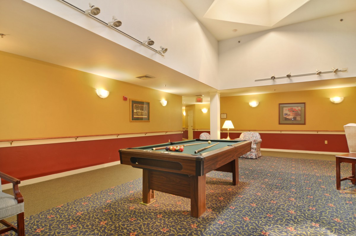 A cozy game room with a pool table under warm lighting.