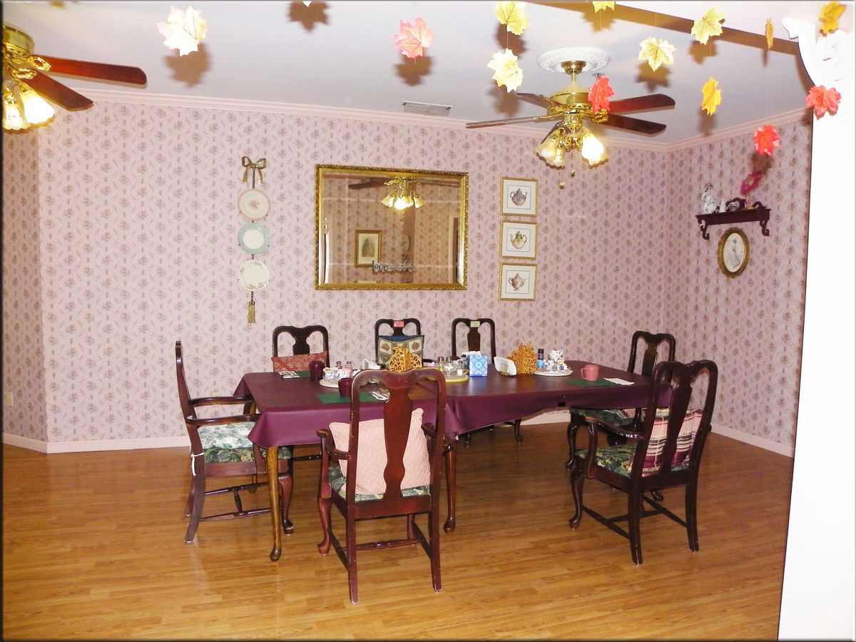 A traditional dining room with a large table, chairs, wallpaper, and decorative items.
