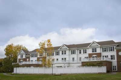 A suburban residential building with a white fence and trees under an overcast sky.