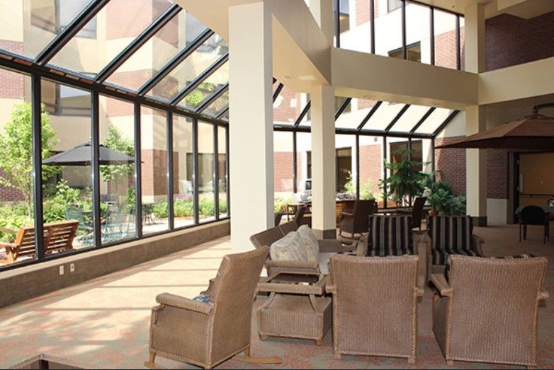 A bright atrium with comfortable seating, featuring large glass windows allowing ample natural light.
