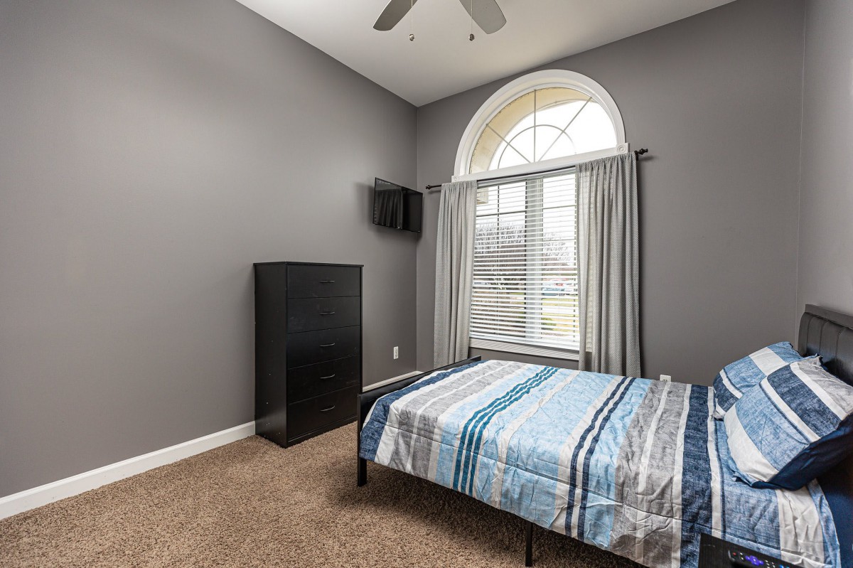 A modern bedroom with a large window, featuring a bed and minimalistic furniture.