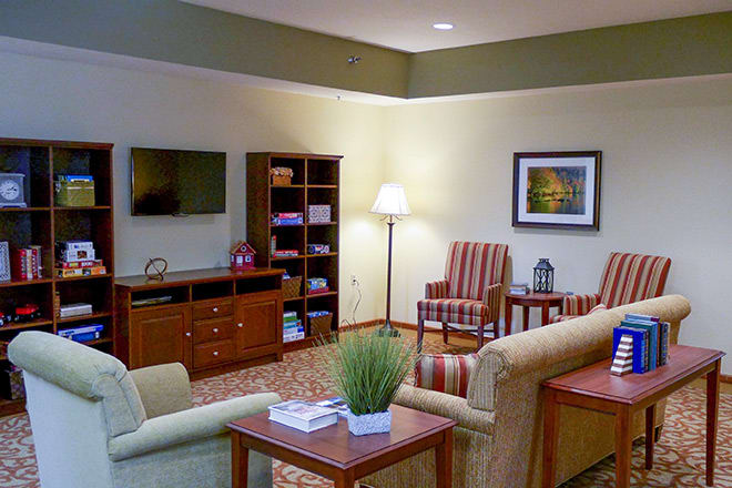 A cozy living room with comfortable seating, a television, and a well-stocked bookshelf.