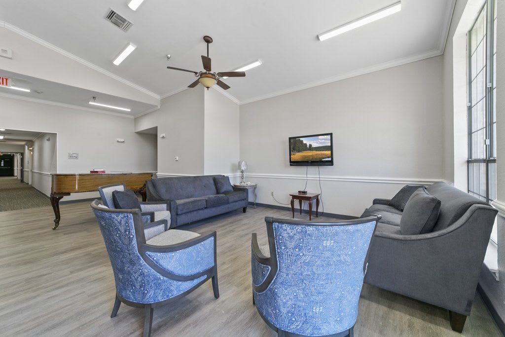 A modern living room with comfortable seating, a television, and a ceiling fan.
