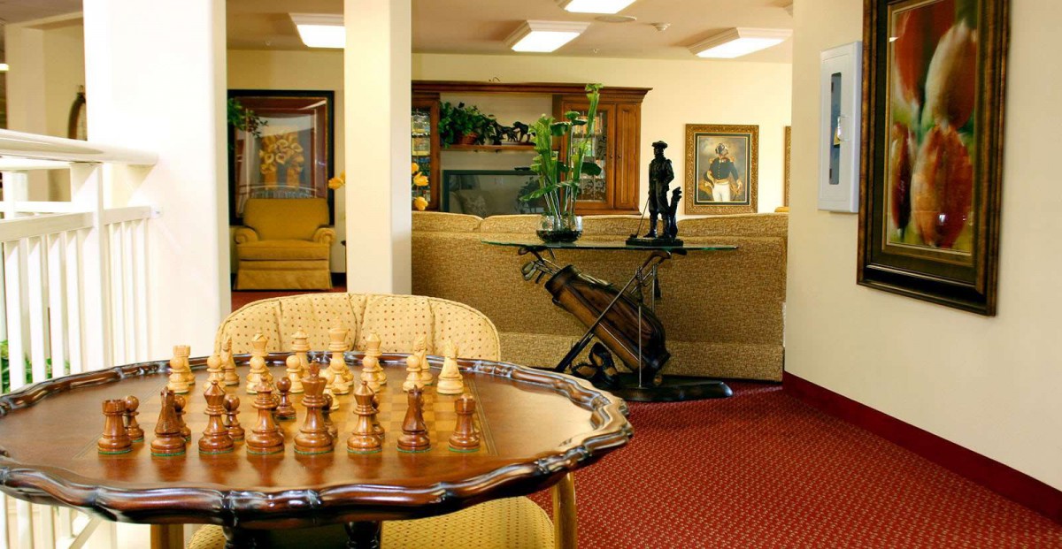 A cozy living room featuring a chess set on a wooden table with elegant furnishings in the background.