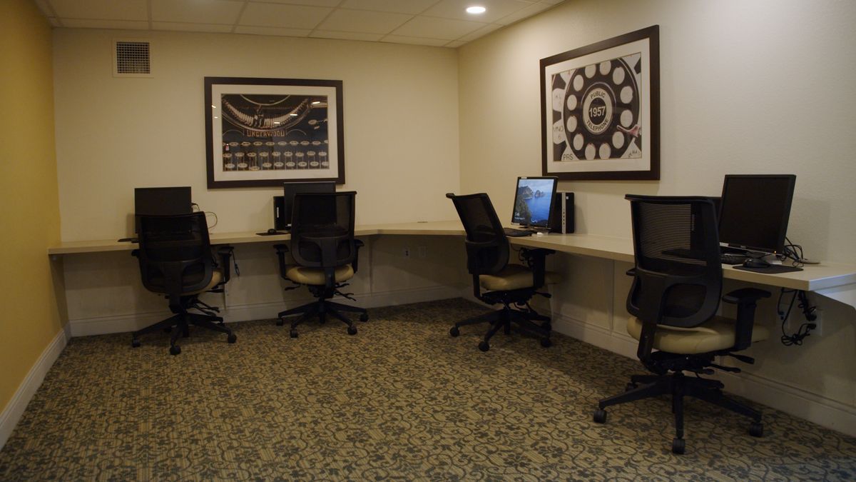 A small office space featuring several computer workstations and chairs.