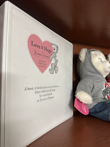 A delightful memory book titled 'Love & Hug' alongside a cozy stuffed bear dressed in a hoodie.