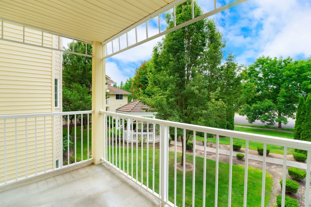 A balcony with a view of lush green trees and surrounding buildings.