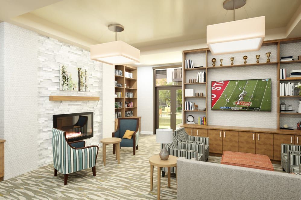 A cozy and modern living room with a fireplace, bookshelves, and a television displaying a football game.