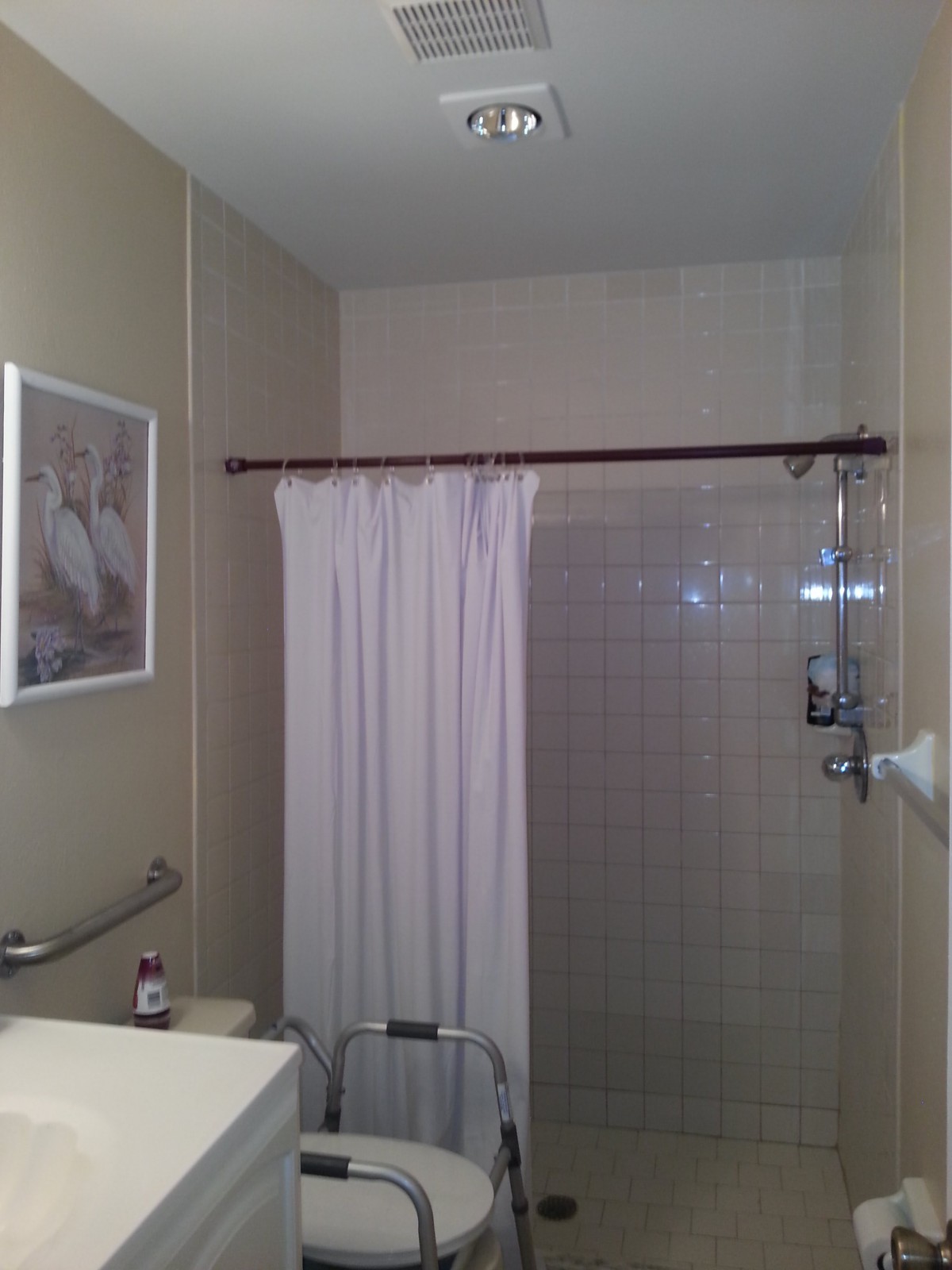 A bathroom with a shower curtain and tiled walls.