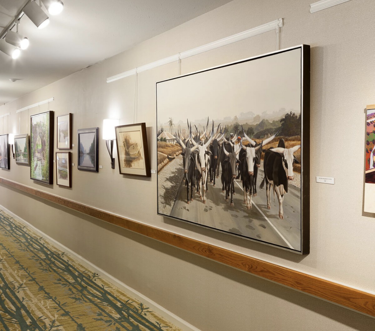 A hallway in an art gallery displaying various paintings on the walls.