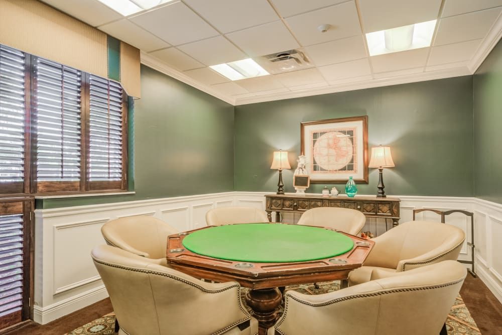 A cozy room featuring a round poker table with green felt and comfortable chairs, complemented by elegant decor.