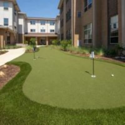 An outdoor putting green beside a modern building.