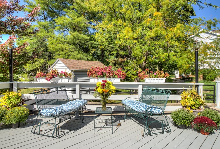 A serene outdoor patio with comfortable seating and vibrant floral arrangements.