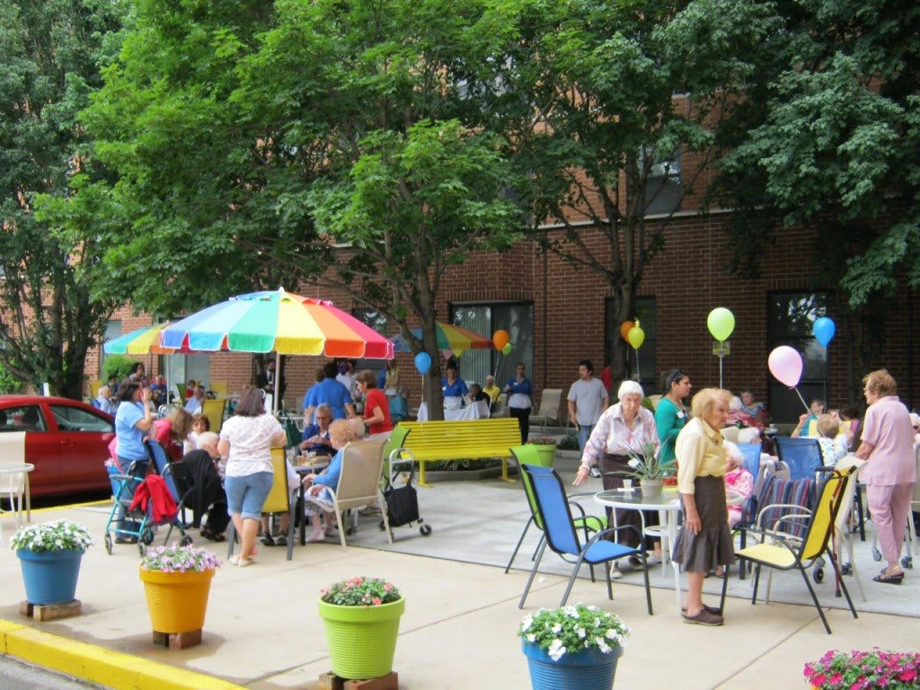 A lively outdoor event with people socializing under colorful umbrellas and balloons.