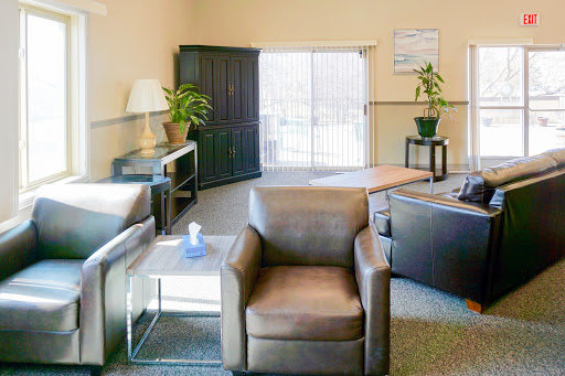 A cozy lounge area featuring comfortable seating, decorative plants, and ample natural light.