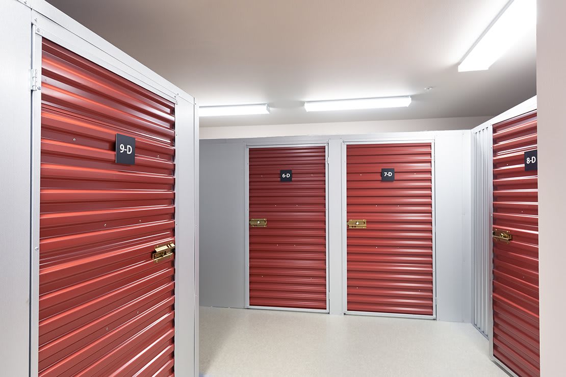 A row of red storage unit doors inside a facility.