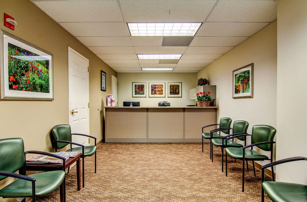 A tidy and organized waiting room with a reception desk and chairs lined up along the walls.
