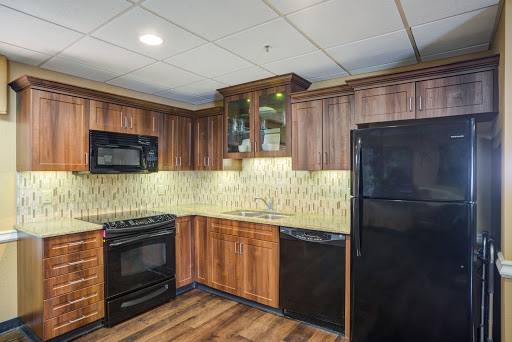 A contemporary kitchen featuring wooden cabinets and black appliances, with a stylish tile backsplash.