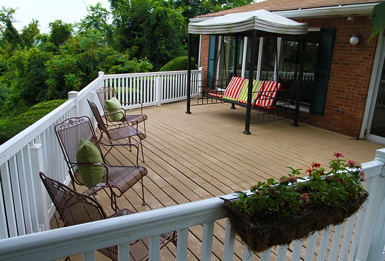 An inviting outdoor deck with cozy seating, a canopy for shade, and potted plants for decoration.