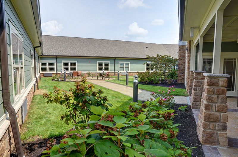 A well-maintained courtyard garden with blooming flowers and a building in the background.