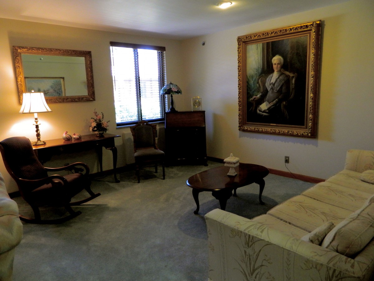A traditional living room with a portrait on the wall and classic furniture.