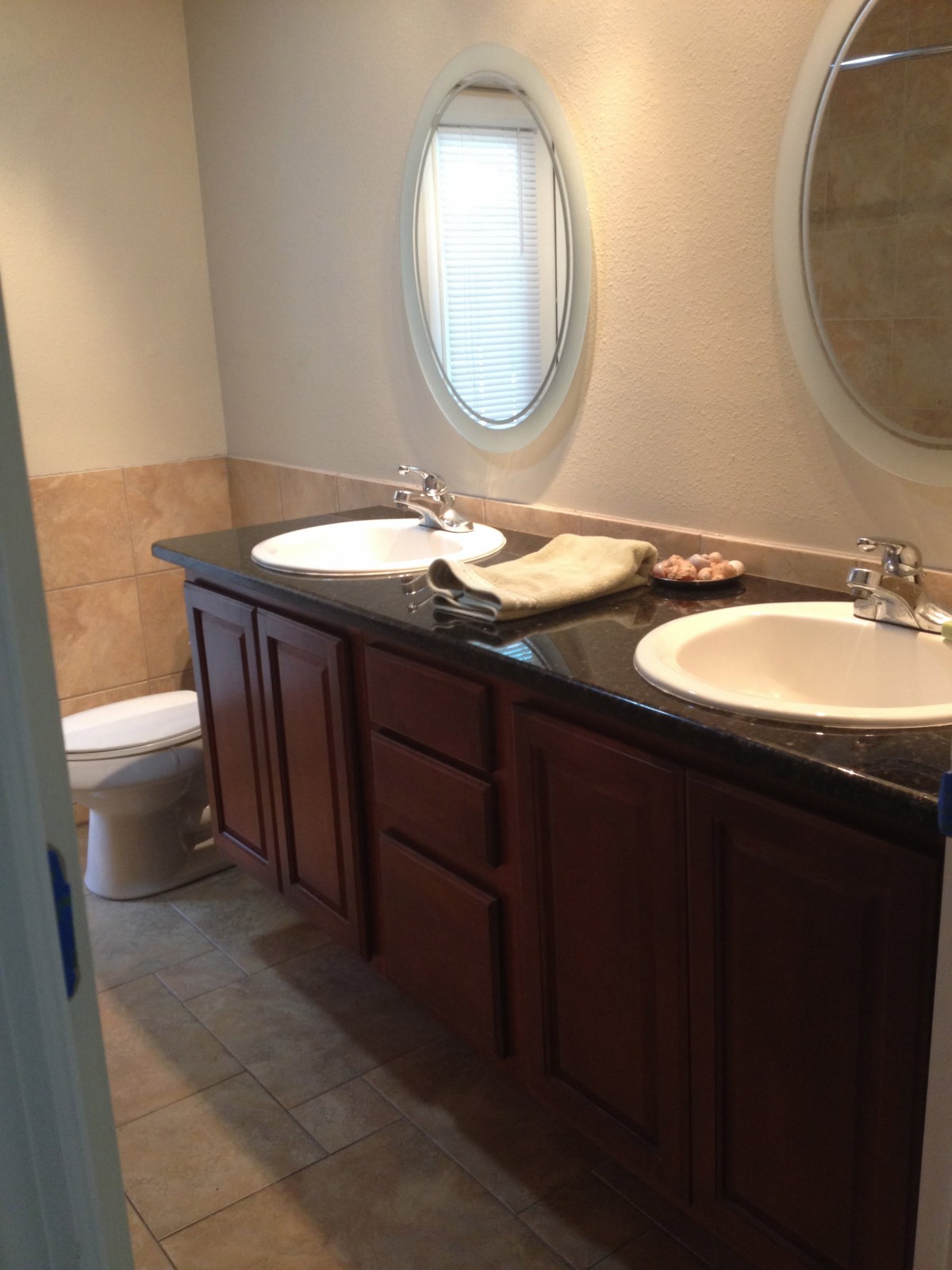 A modern bathroom featuring a double sink vanity with mirrors and a toilet.