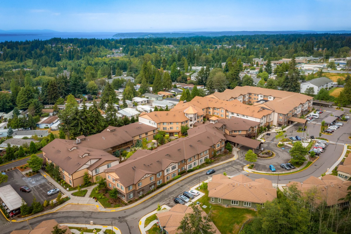 Aerial view of a large building complex surrounded by greenery in a suburban area.