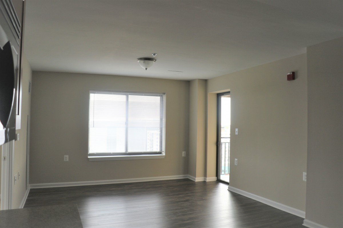 An empty room with a window and door, featuring hardwood floors.