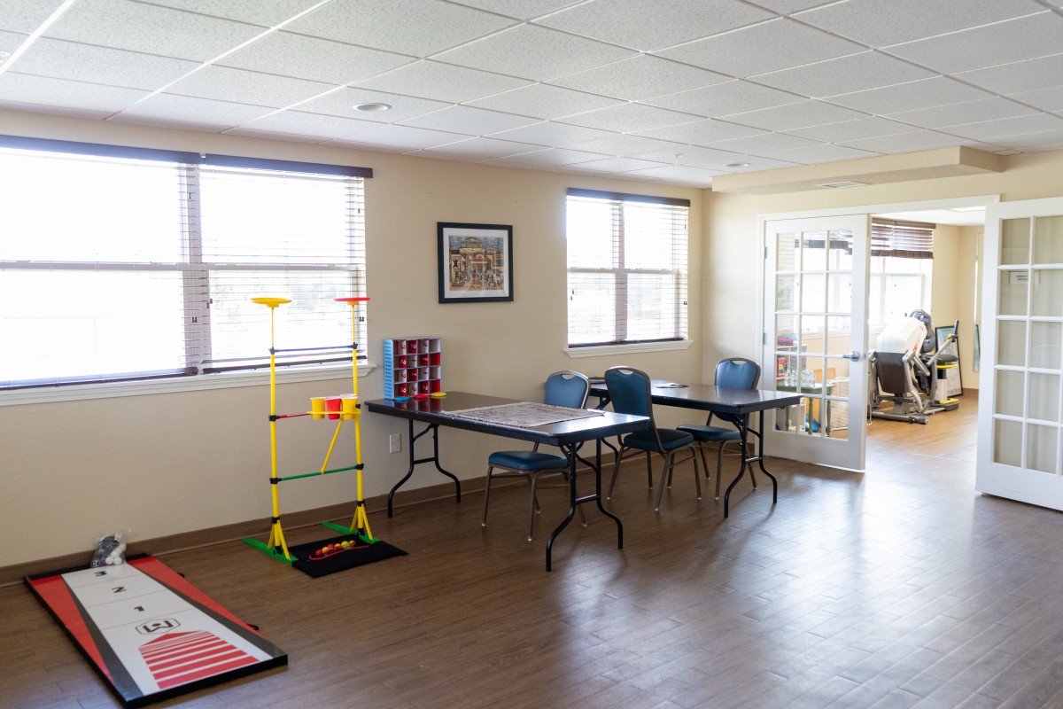 A recreational room with tables, chairs, and games.