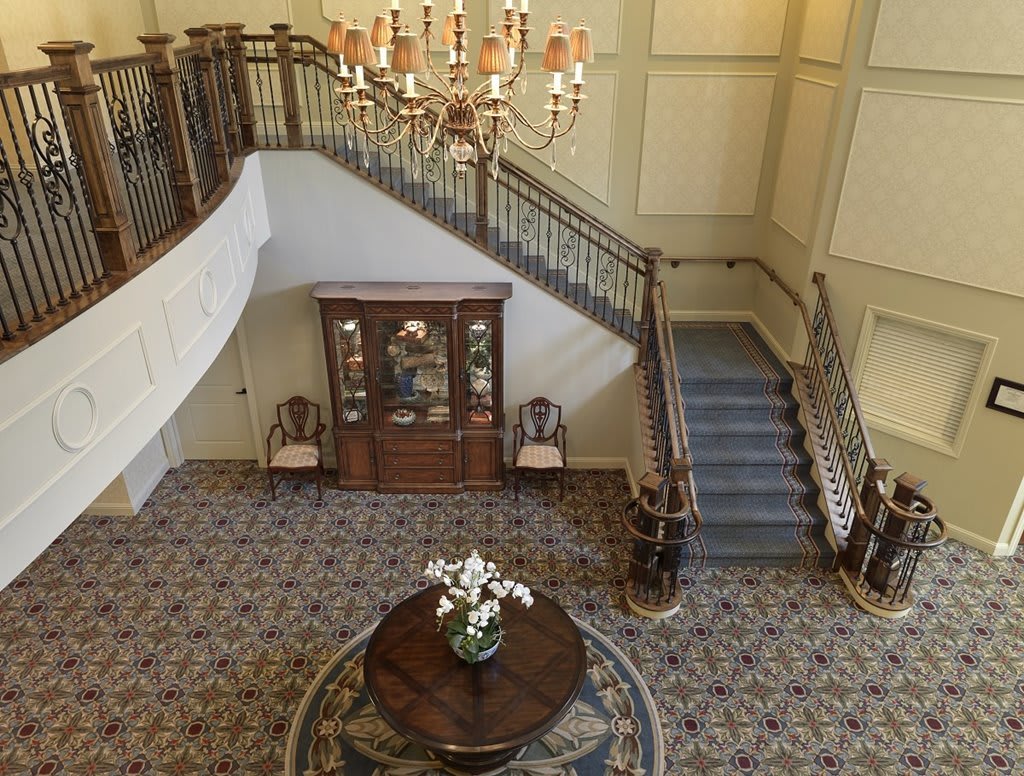 A luxurious interior featuring a grand staircase, chandelier, and elegant furnishings in the foyer.