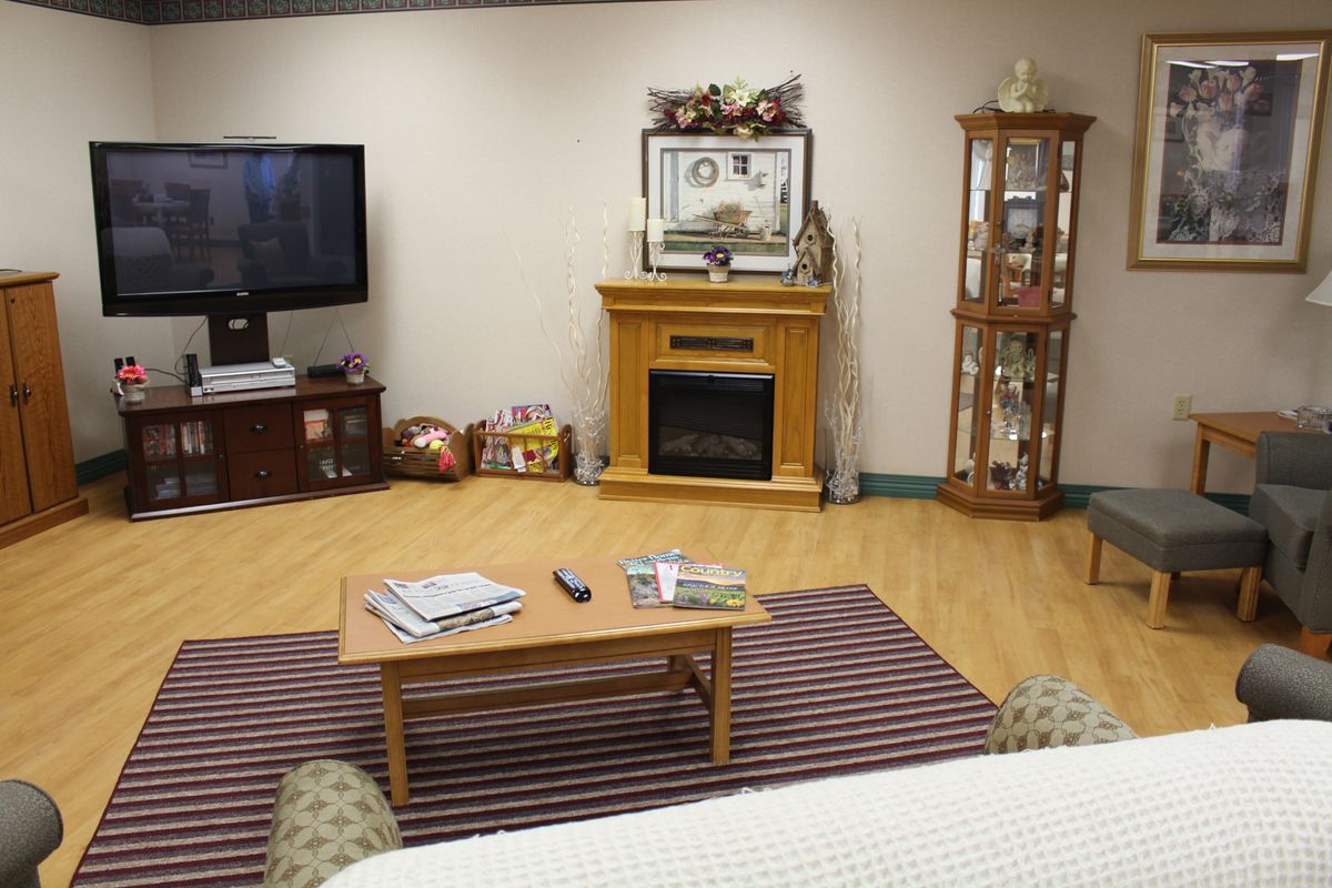 A cozy living room featuring a fireplace, television, and a coffee table with magazines.
