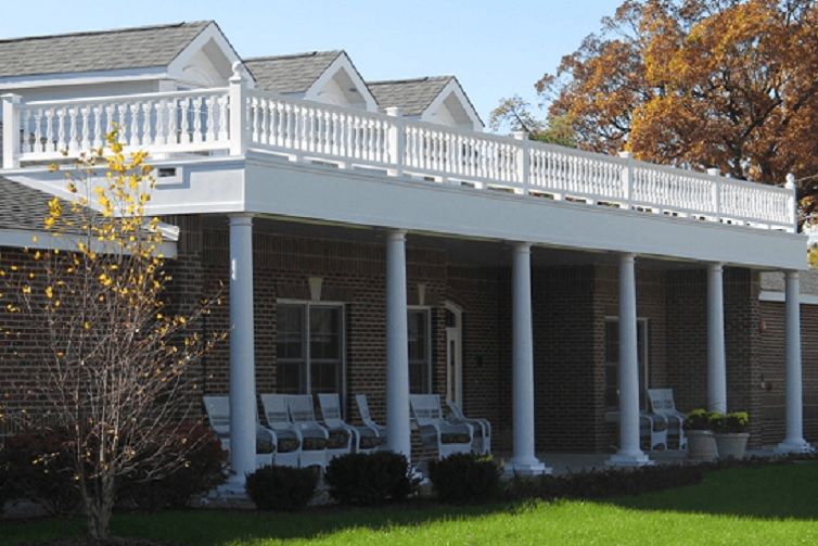 A house with a large porch featuring columns and an upper balcony.
