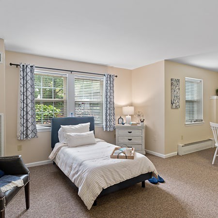 A cozy and well-lit bedroom with a single bed, decorative curtains, and modern furnishings.
