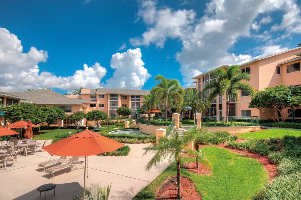 A luxurious tropical resort with palm trees and vibrant outdoor spaces under a bright blue sky.
