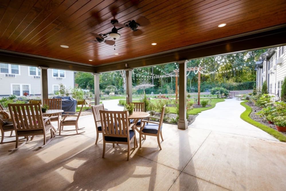 A covered patio with wooden furniture overlooking a garden.