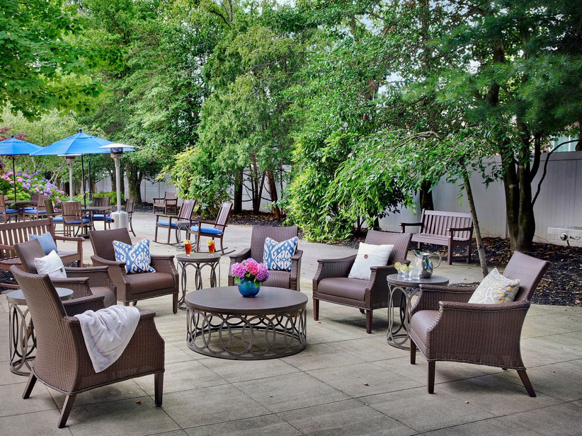 A charming outdoor patio with comfortable seating surrounded by lush greenery.