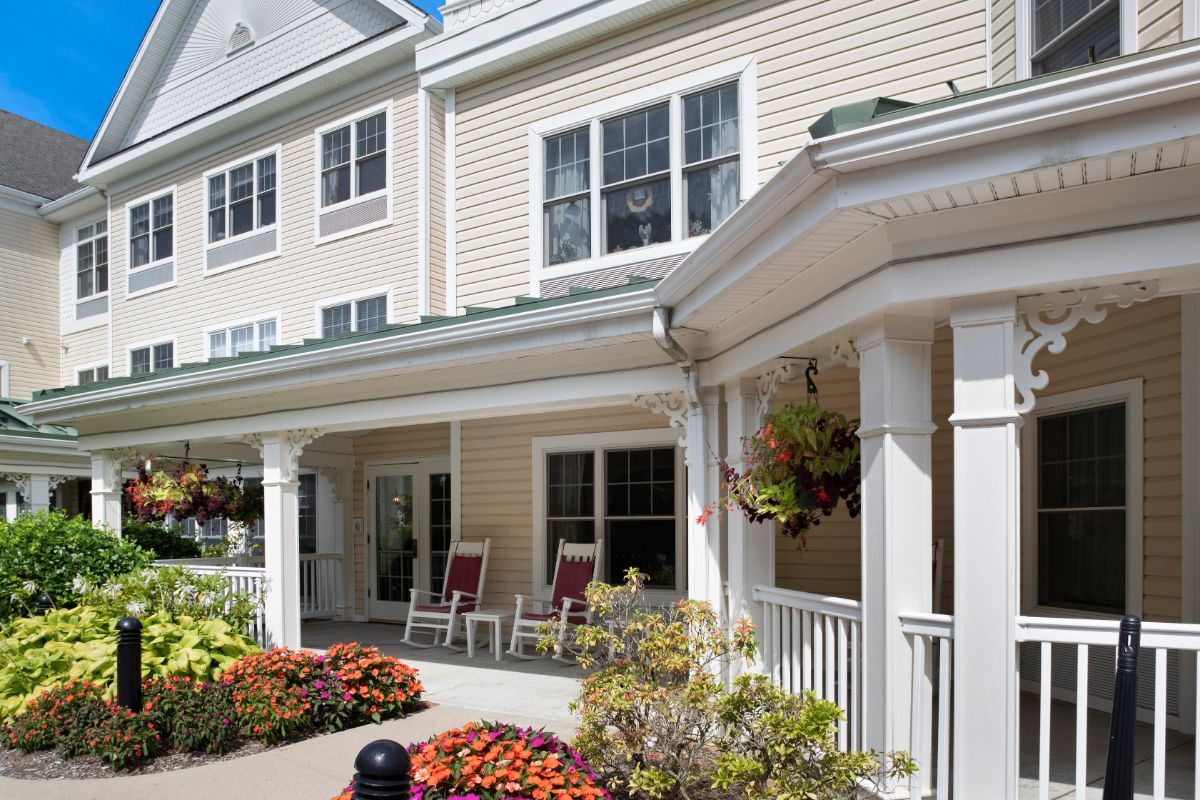 A charming residential building with a welcoming porch and colorful flower arrangements.