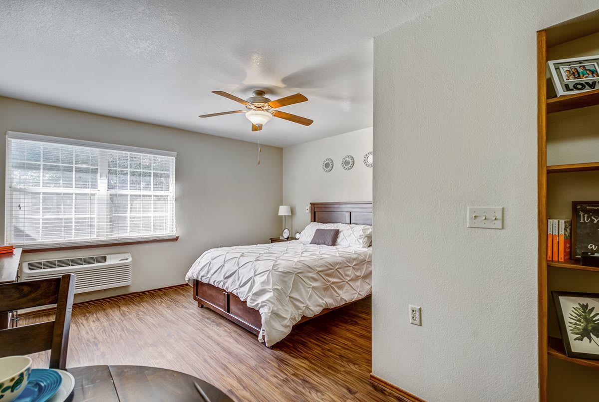 A cozy bedroom with a large bed, ceiling fan, and wooden flooring.