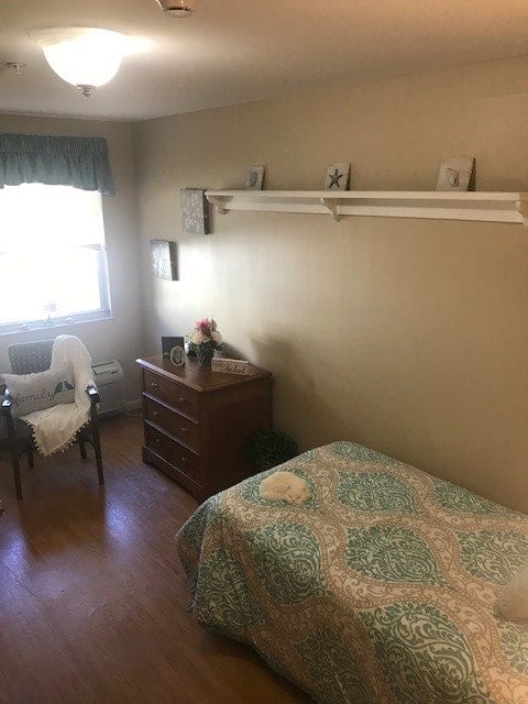 A cozy, minimalist bedroom with a single bed, dresser, and window.