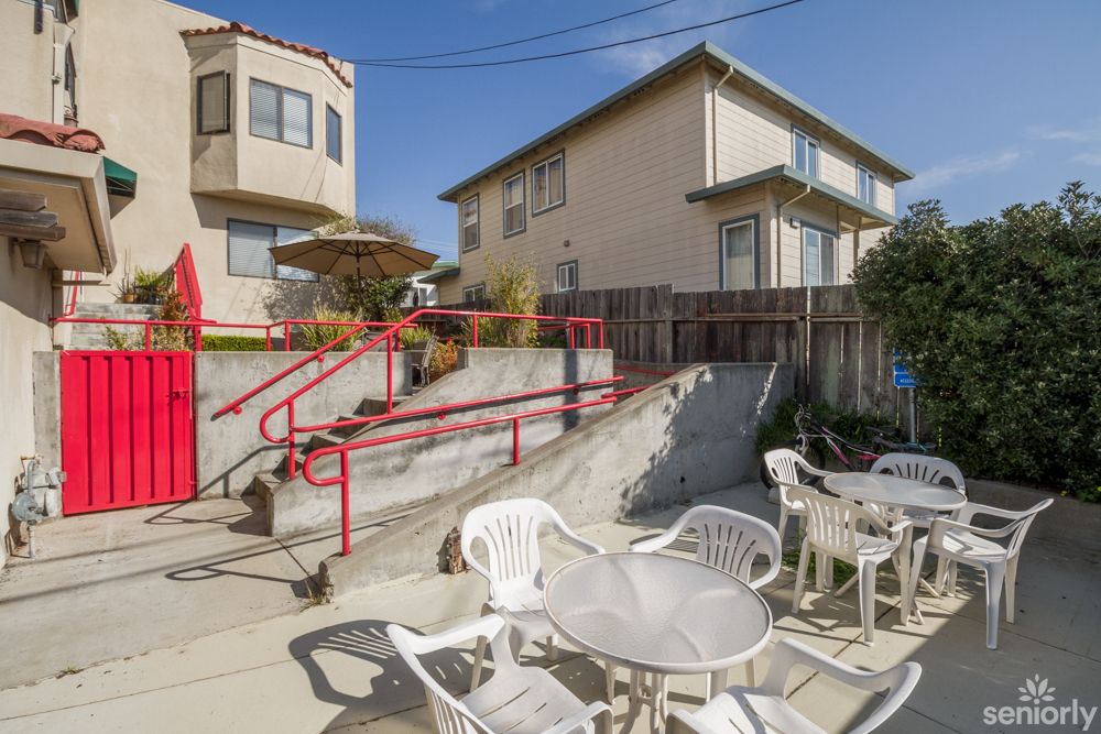 Outdoor patio area with tables, chairs, and stairs in a residential setting.