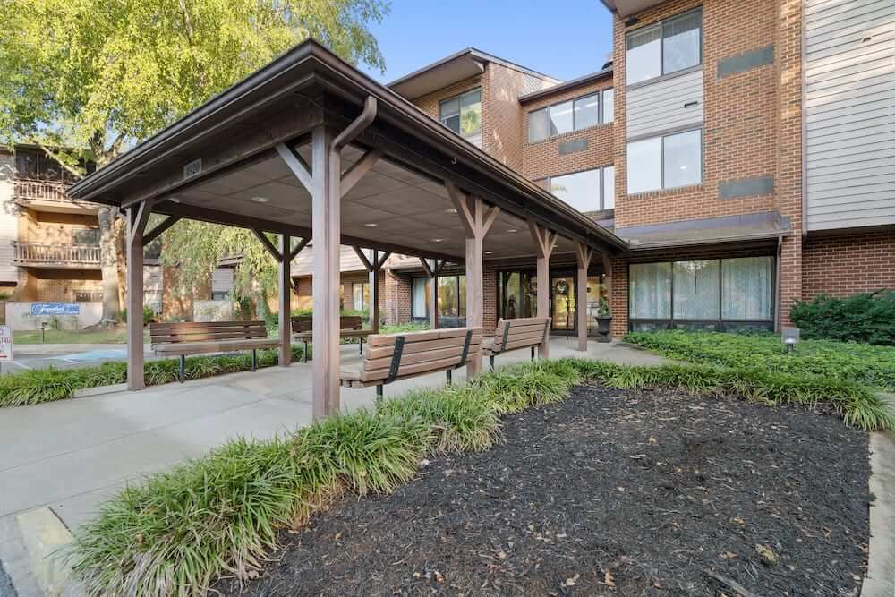 A view of a residential building with a covered walkway and benches.