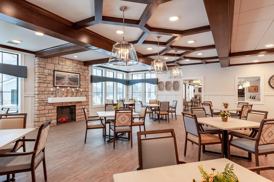 A modern dining room interior with elegant furniture and lighting, featuring large windows and a stone fireplace.