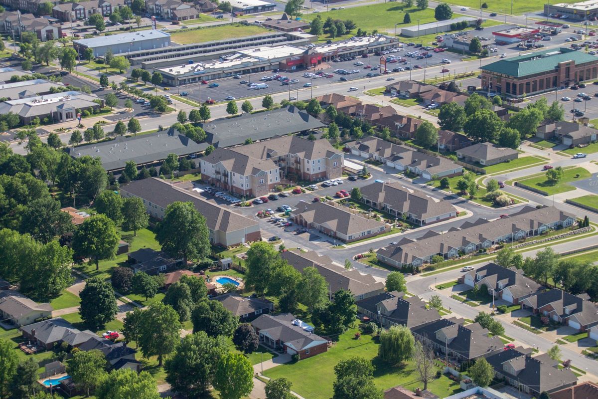 An aerial view of a suburban residential neighborhood with houses, streets, and greenery.