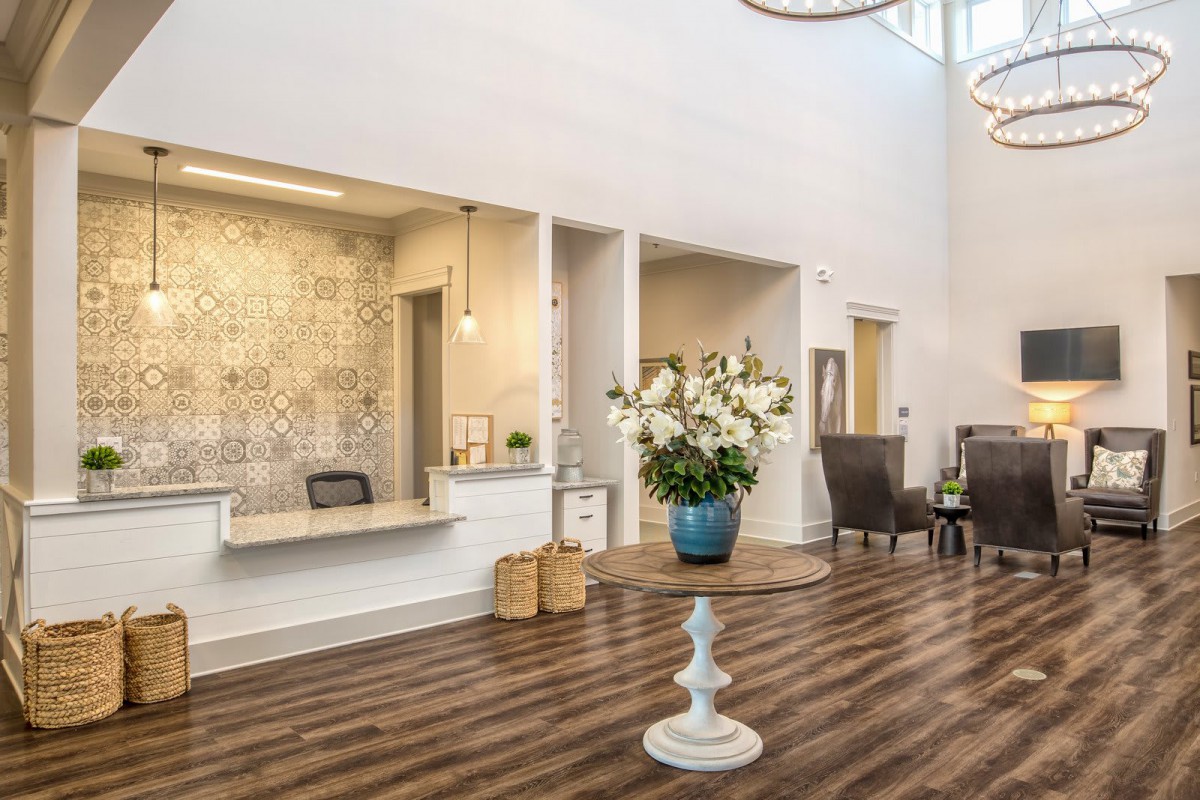 A modern reception area with a wooden floor and elegant flower arrangement.