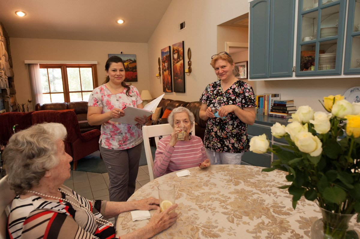 Healthcare workers engaging with elderly residents in a nursing home setting.