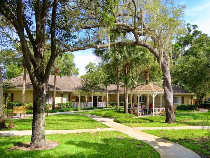 A peaceful outdoor setting with a house, gazebo, and lush greenery.
